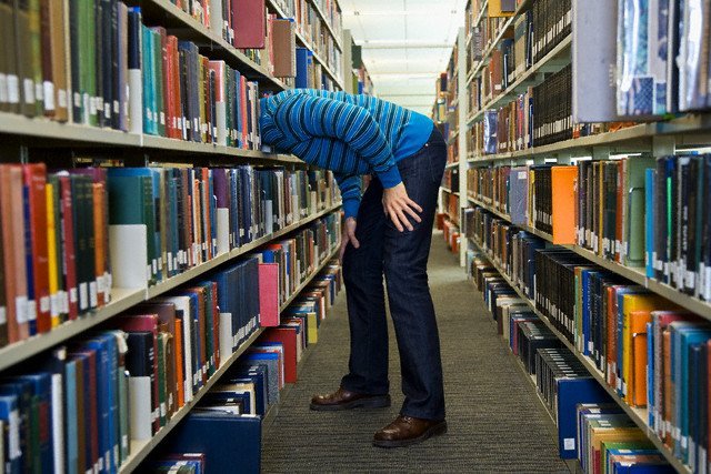 man searching for purpose book in library