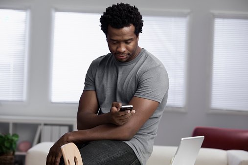 selfless Black man using cell phone in home office