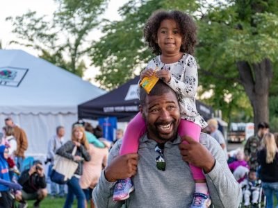dad carrying daughter on his shoulder at carnival