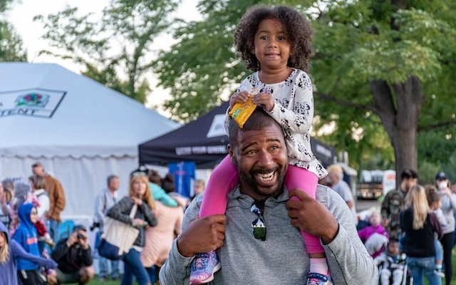 dad carrying daughter on his shoulder at carnival