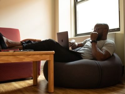 man doing remote work sitting on couch with laptop computer