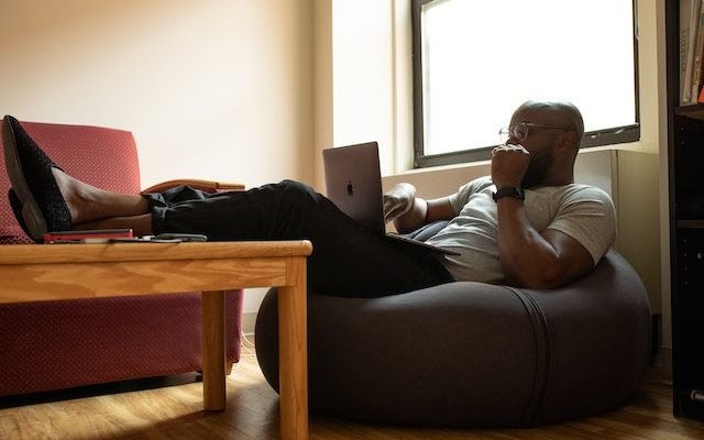 man doing remote work sitting on couch with laptop computer