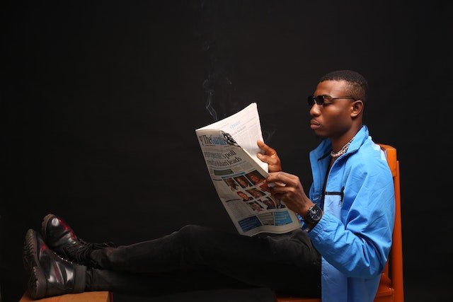 A Man wearing a wristwatch and Reading A News Paper