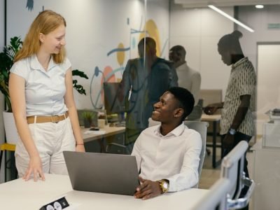 man with influence in his team sitting and talking to a female co-worker who is standing