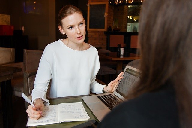 woman with eecutive voice presenting business strategy to senior colleague with laptop computer and notebook in front of her