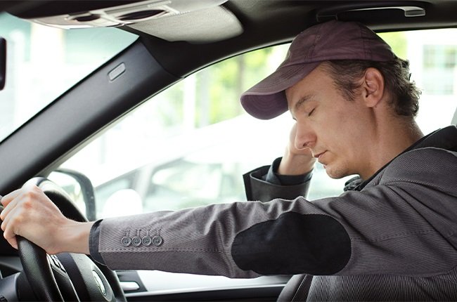 man in car struggling to stay awake at the wheel