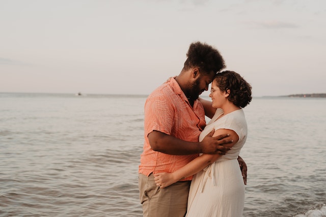 husband and wife embracing beside sea