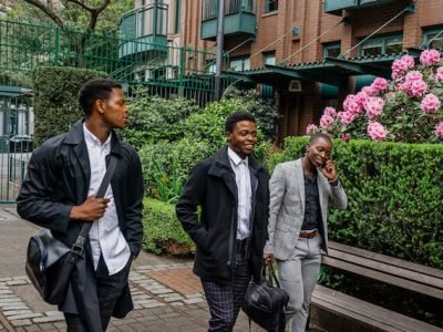 three young african men in formal wear walking side by side on street and embracing their masculinity