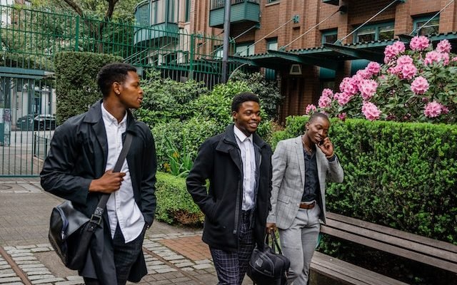 three young african men in formal wear walking side by side on street and embracing their masculinity