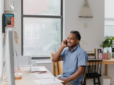 Effective communicator sitting at desk in office, talking on phone