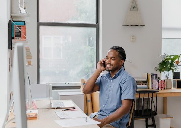 Effective communicator sitting at desk in office, talking on phone