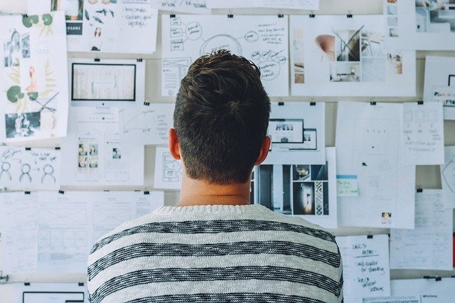 man standing in front of wall with notes pasted on it thinking of how to turn his business ideas into reality