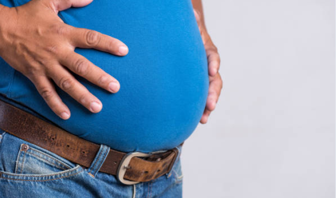 man with potbelly holding his stomach