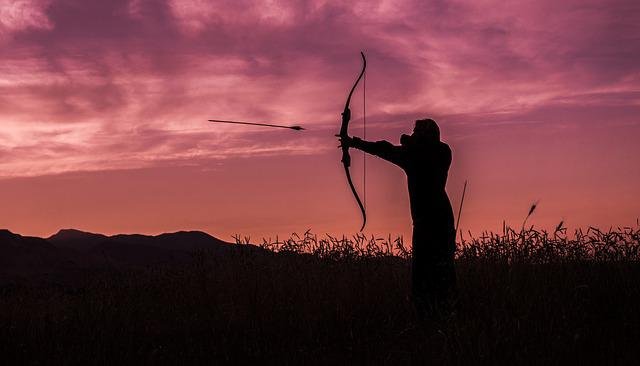 silhouette of young man with crossbow shooting an arrow
