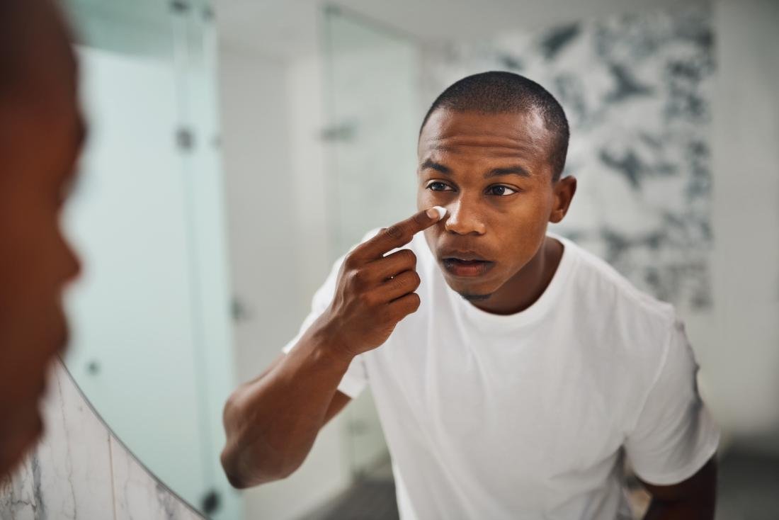 man examining dark circles in mirror