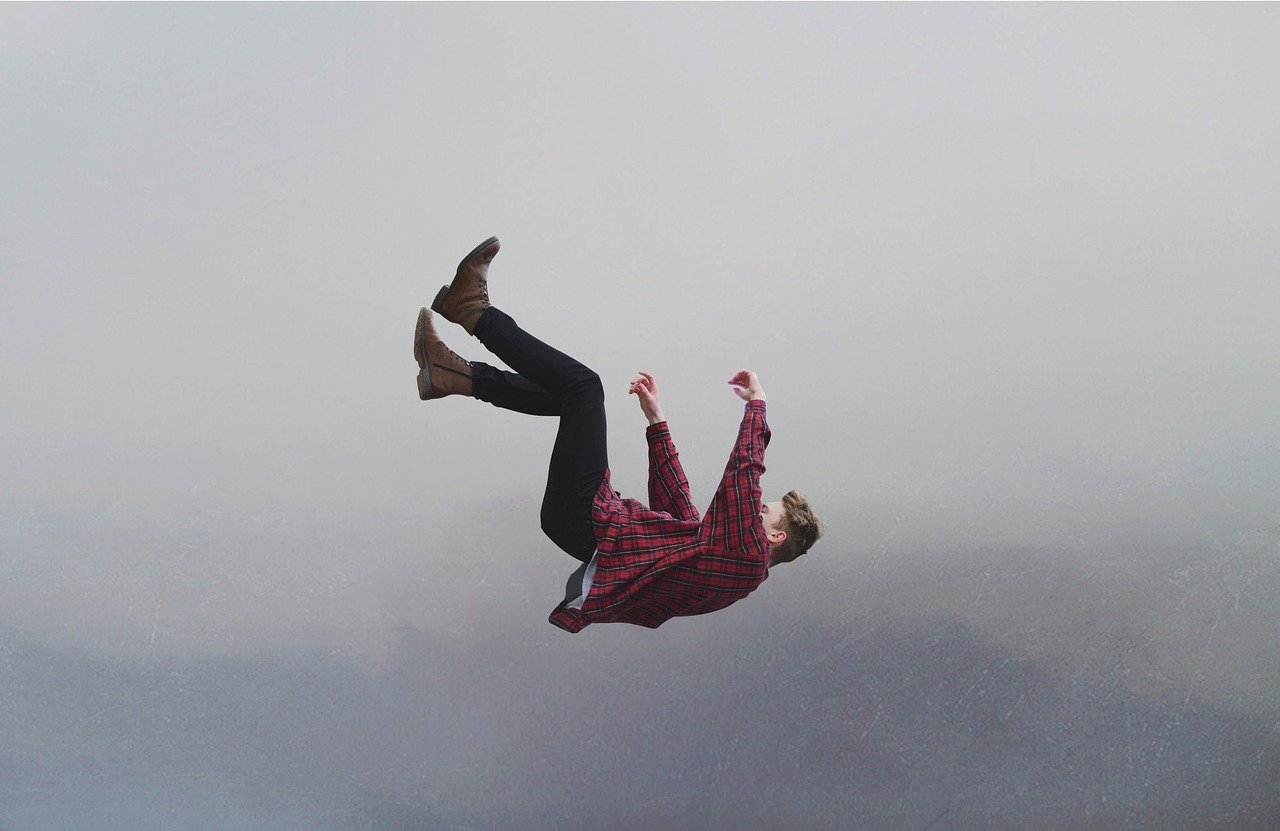 man in red shirt and trousers who fails to grow in tough times falling through grey mist