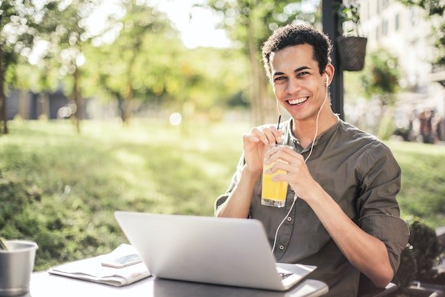 healthy man sitting with laptop and juice in park