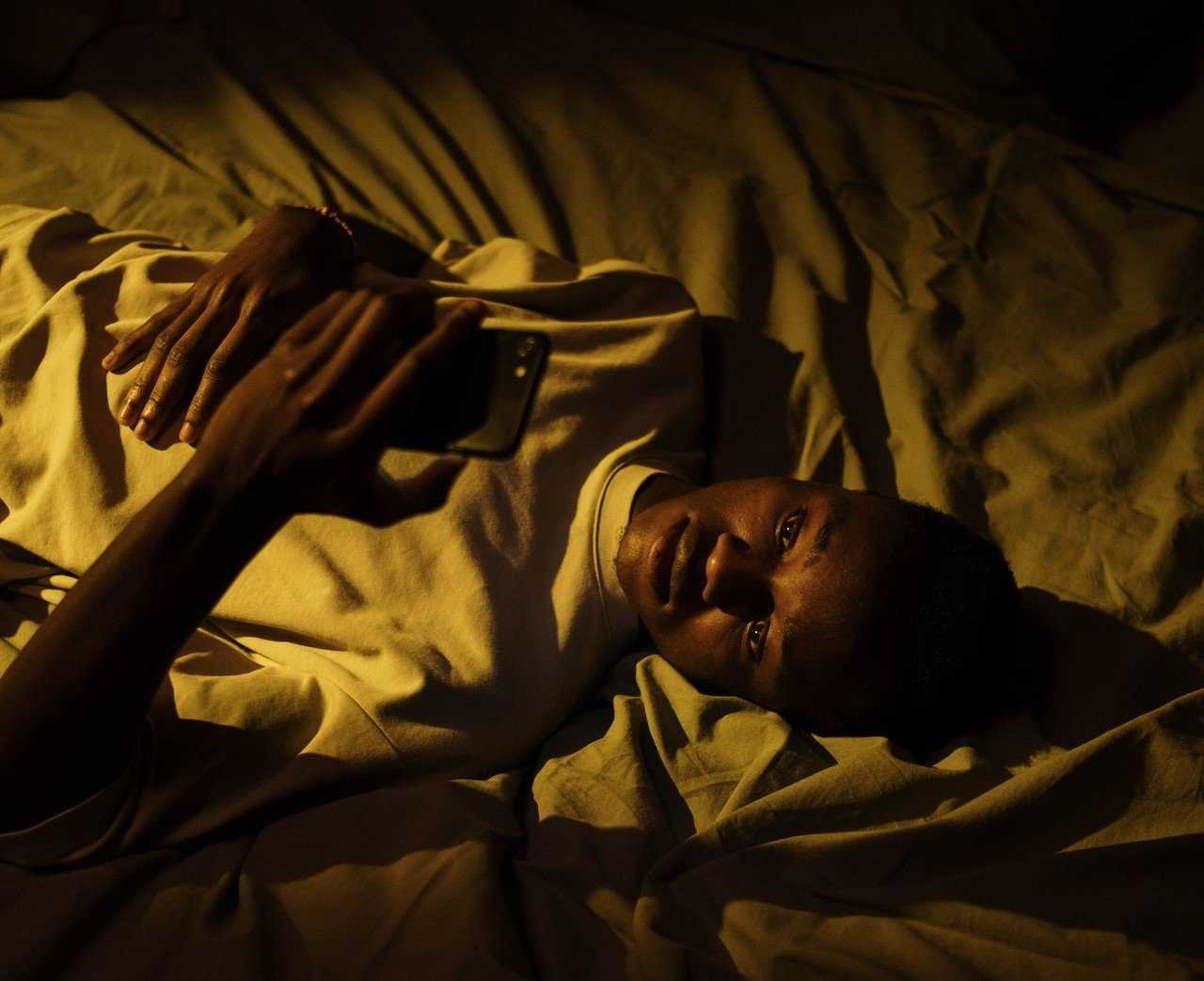 a man lying in bed at night using a phone