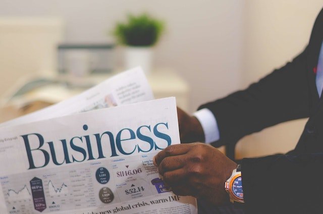Business man reading how to attract new cstomers in white and blue business paper