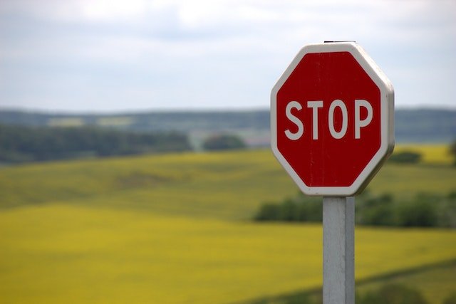 stop sign on green field as warning against dangerous habits